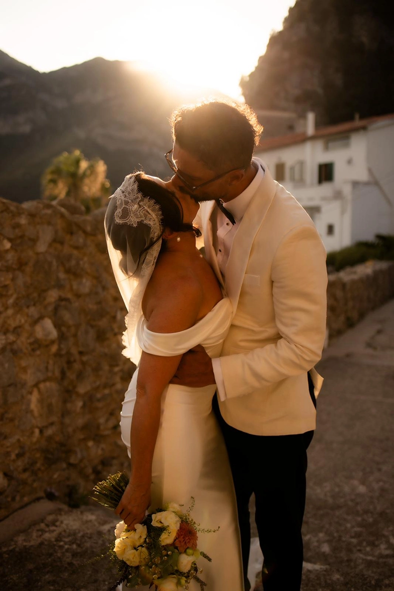 Newlyweds sharing a romantic kiss in the warm sunset light after their wedding ceremony on the Amalfi Coast.