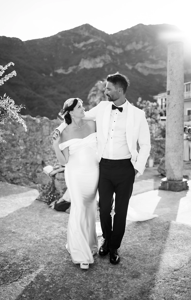 Black-and-white photograph of newlyweds walking together among the historic ruins of Scala on the Amalfi Coast.