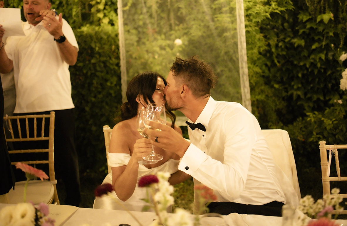 Newlyweds sharing a kiss during their outdoor wedding dinner on the Amalfi Coast.