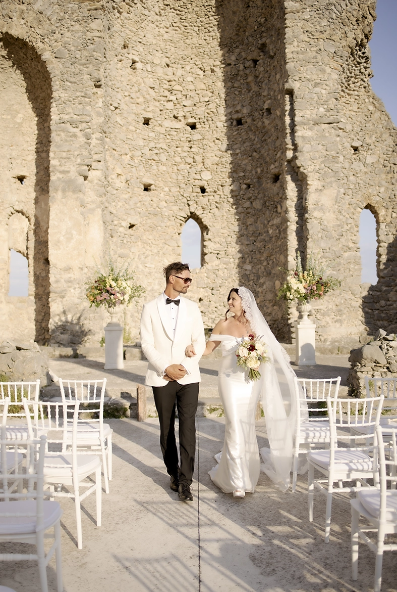 Bride and groom walking together after their wedding ceremony among the historic ruins of Sant’Eustachio in Scala.