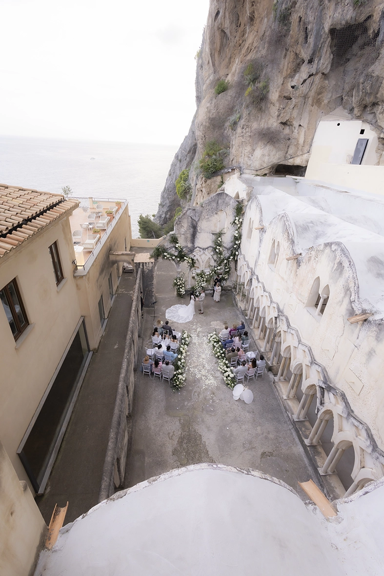 Aerial view of an intimate wedding ceremony at Anantara Convento di Amalfi beside the Mediterranean Sea.