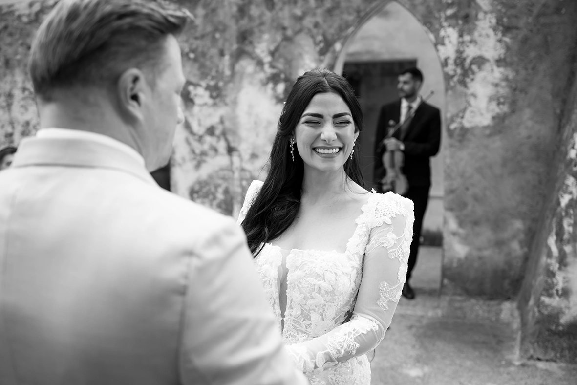 Black-and-white photograph of the bride smiling at the groom during their wedding ceremony in Scala.